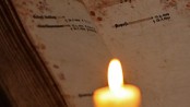 Kerze vor einem Totenbuch